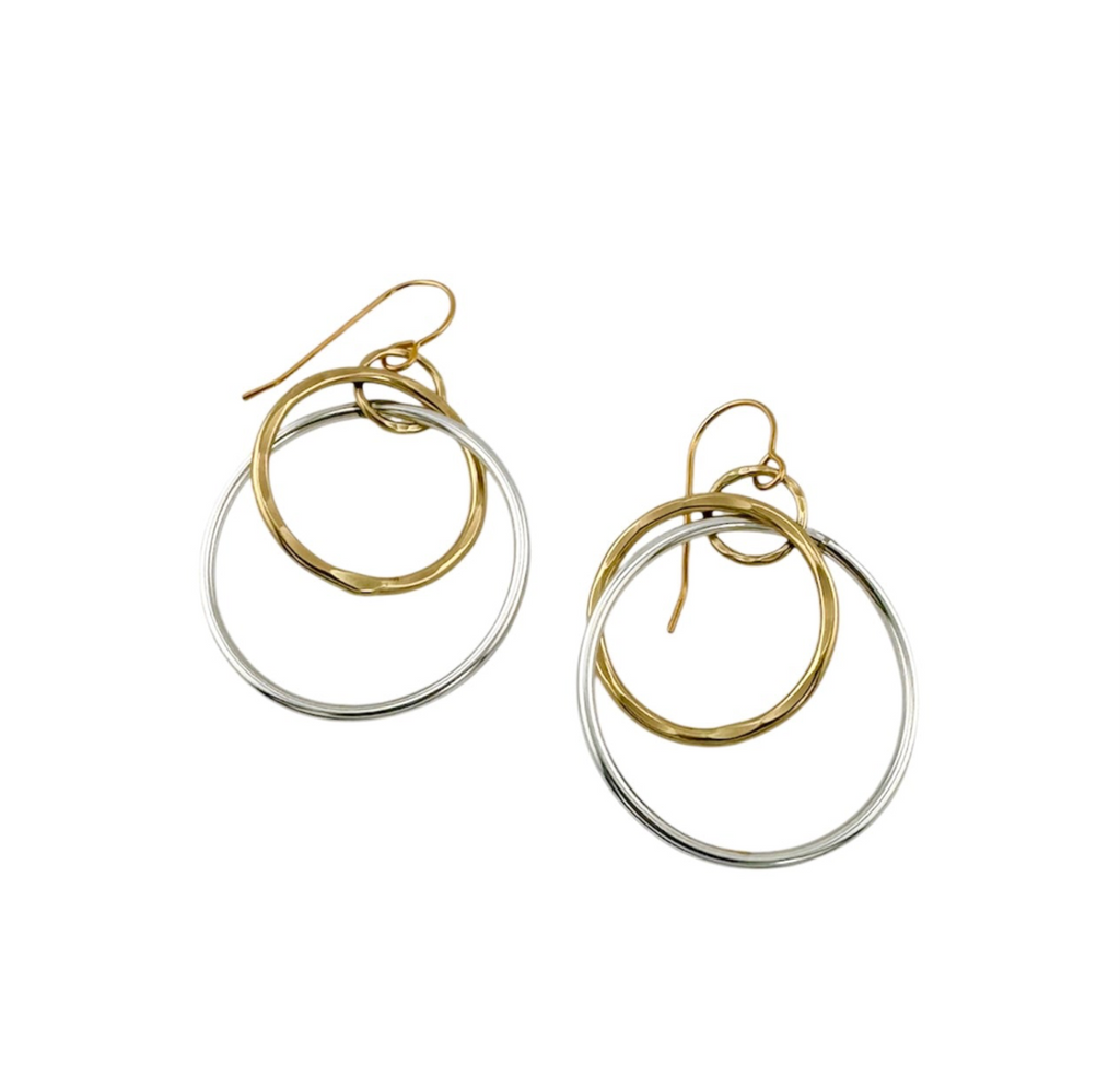 Large silver circle and smaller gold circle dangle from gold hook earring 