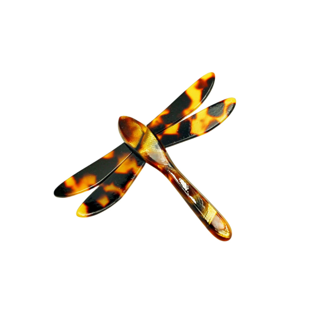 Tortoiseshell dragonfly-shaped hair clip on a beige background