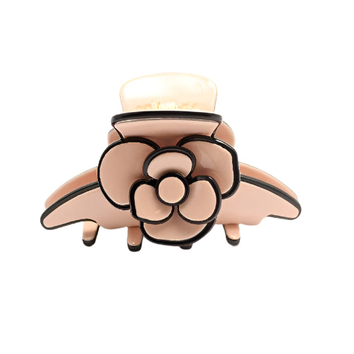 Pink hair clip with black floral design on a white background
