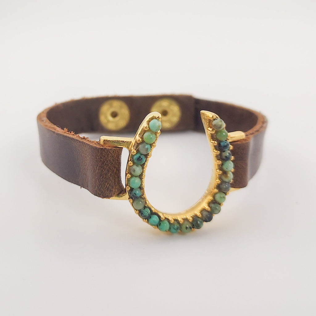 African Turquoise Horseshoe Leather Bracelet in Gold three quarter view facing toward the left over off white background