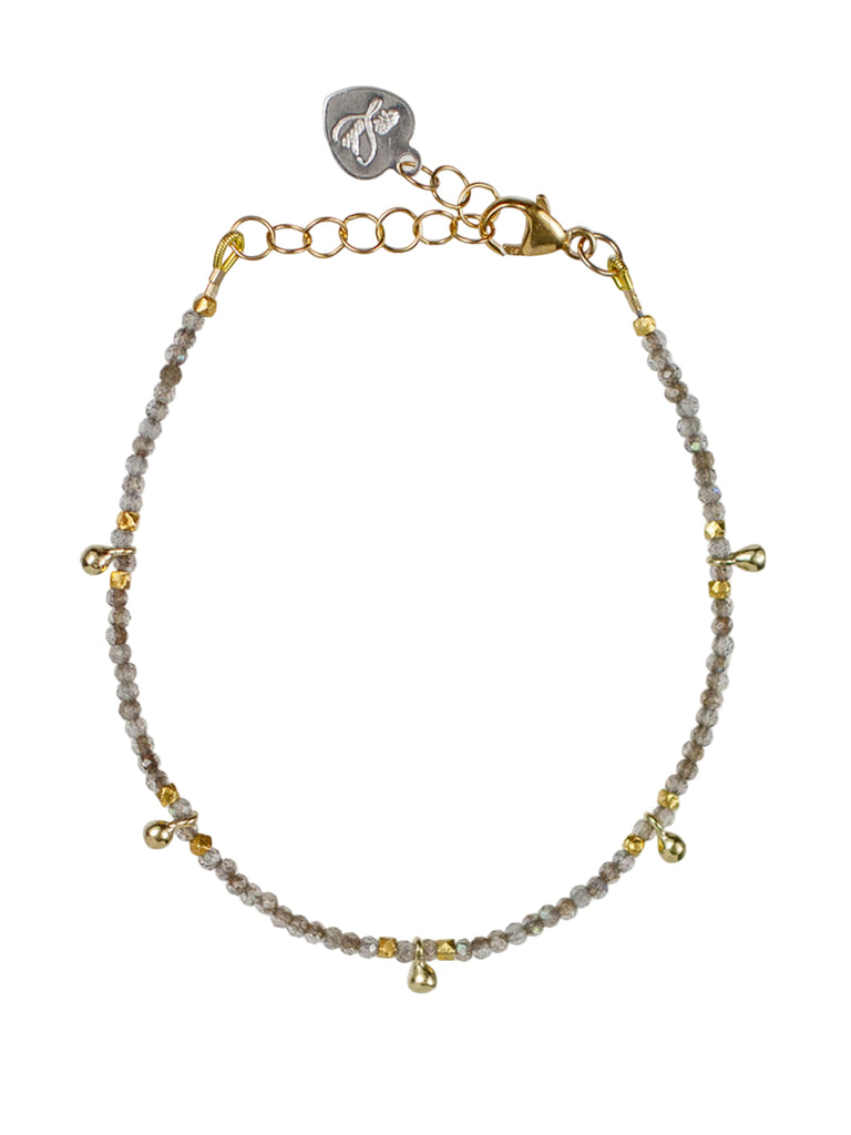 Bracelet with gold and silver chain, gray beads, and a small tag on a white background