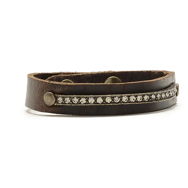 A brown leather bracelet with a series of round Swarovski crystals embellished with a diamond pattern, featuring a brass finish and a snap closure.