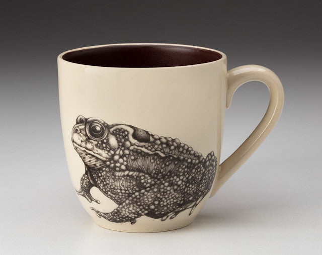 Ceramic mug with a black and white frog illustration on a beige background