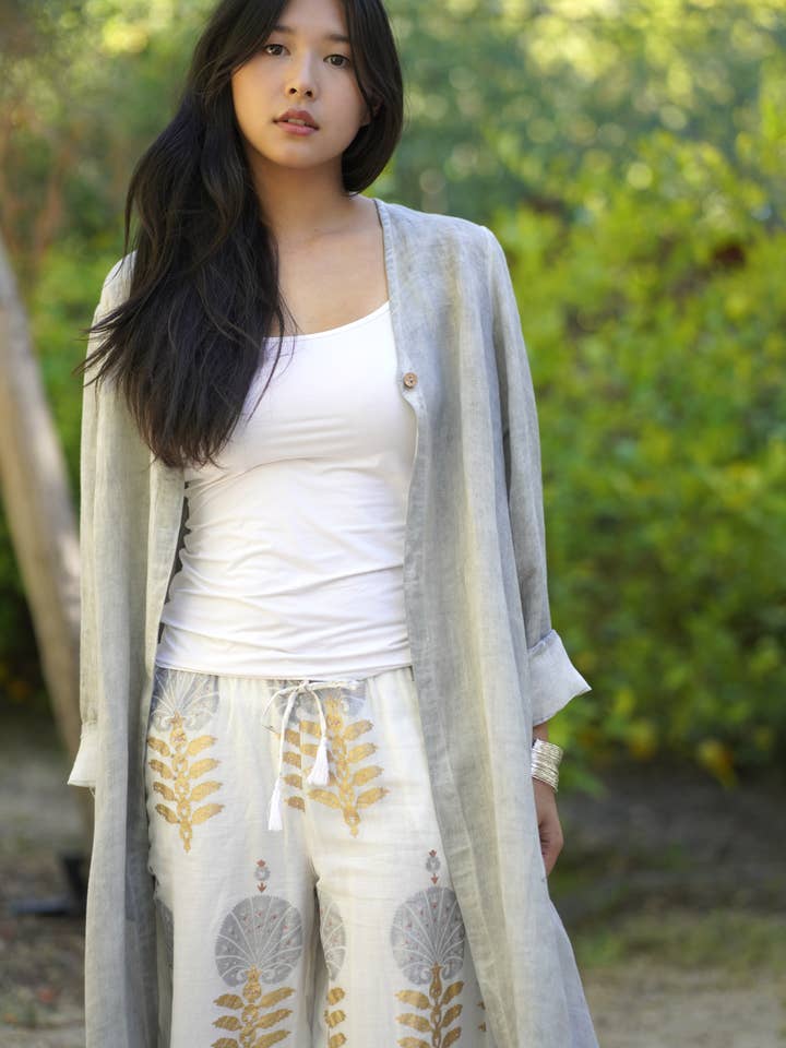 Woman wearing a white top and light-colored cardigan with floral patterns outdoors.