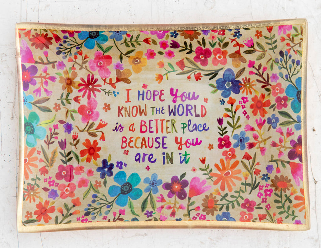 Decorative mat with floral design and motivational quote on a white surface with keys and flowers.