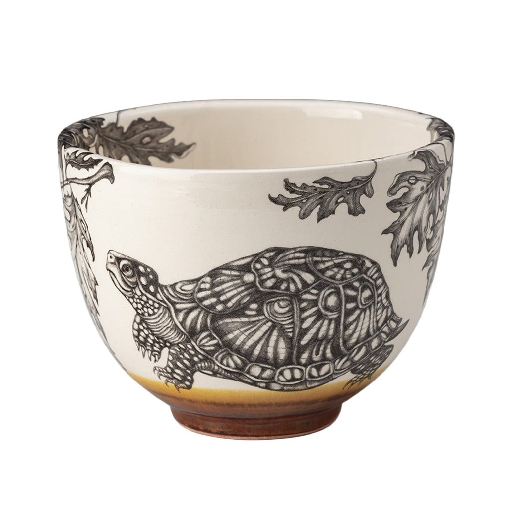 Ceramic bowl with turtle and leaf design on a gray background