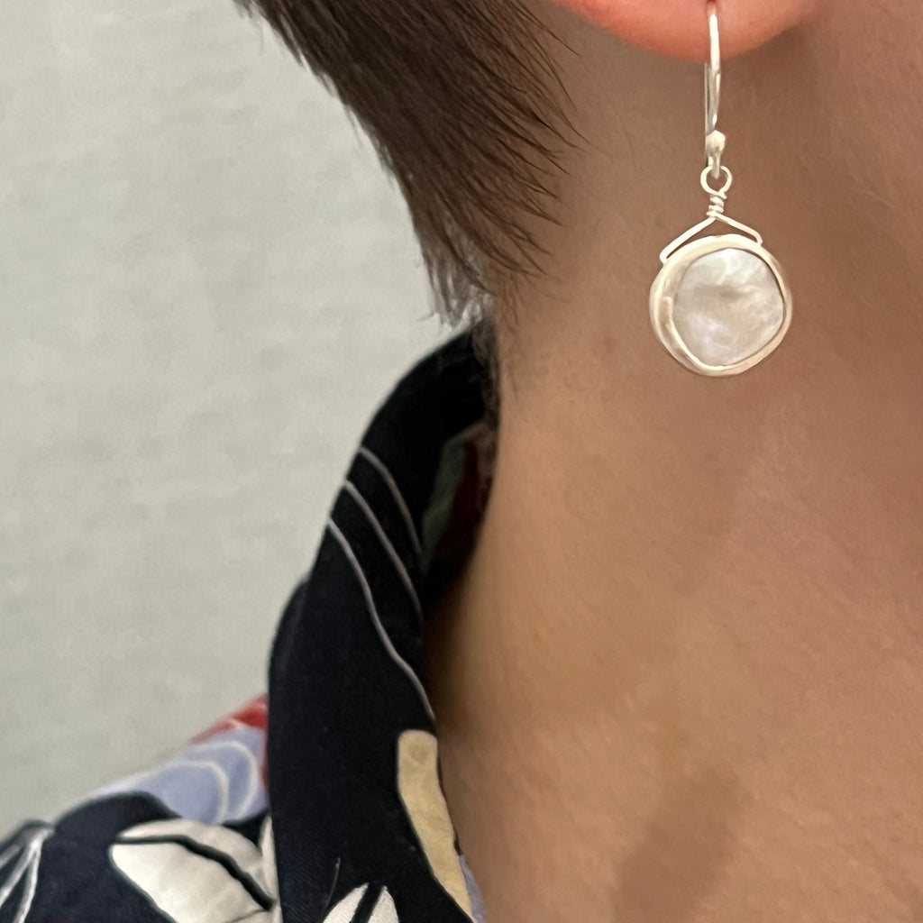 Close-up of an earring worn by a person with a blurred background