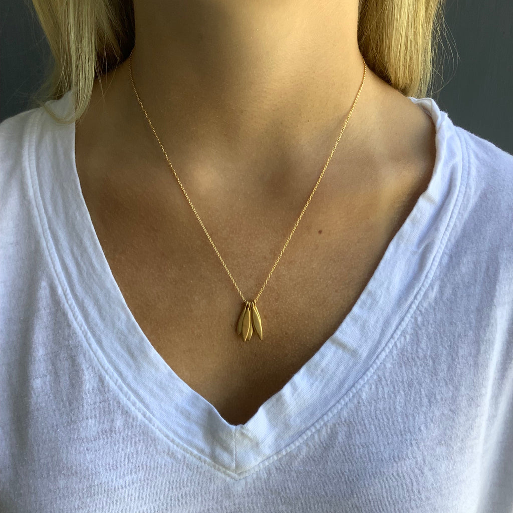 Close-up of a gold necklace on a person wearing a white top.