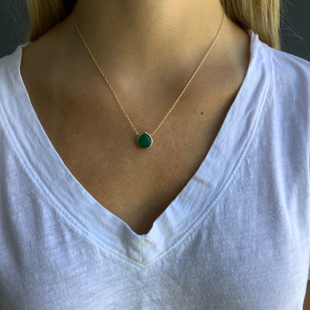 Close-up of a green gemstone necklace on a white shirt
