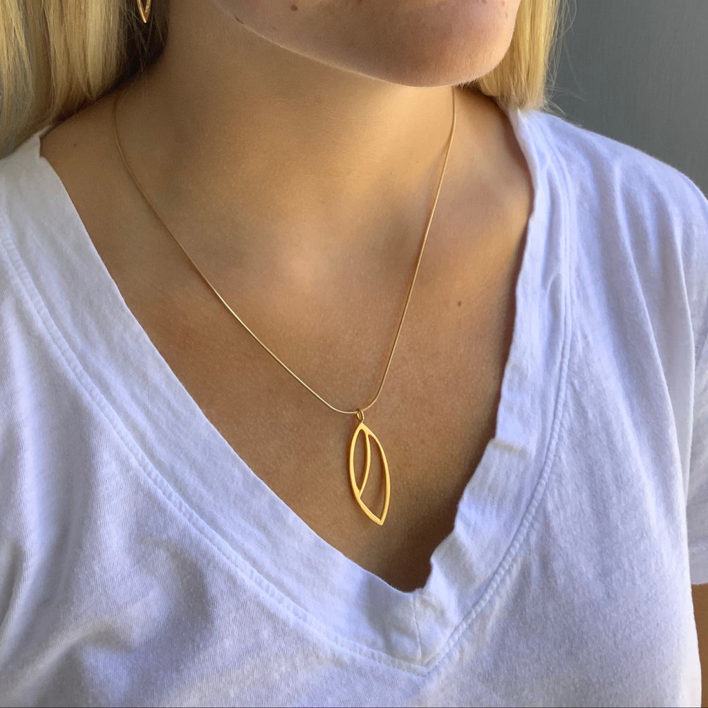 Woman wearing a gold necklace against a neutral background