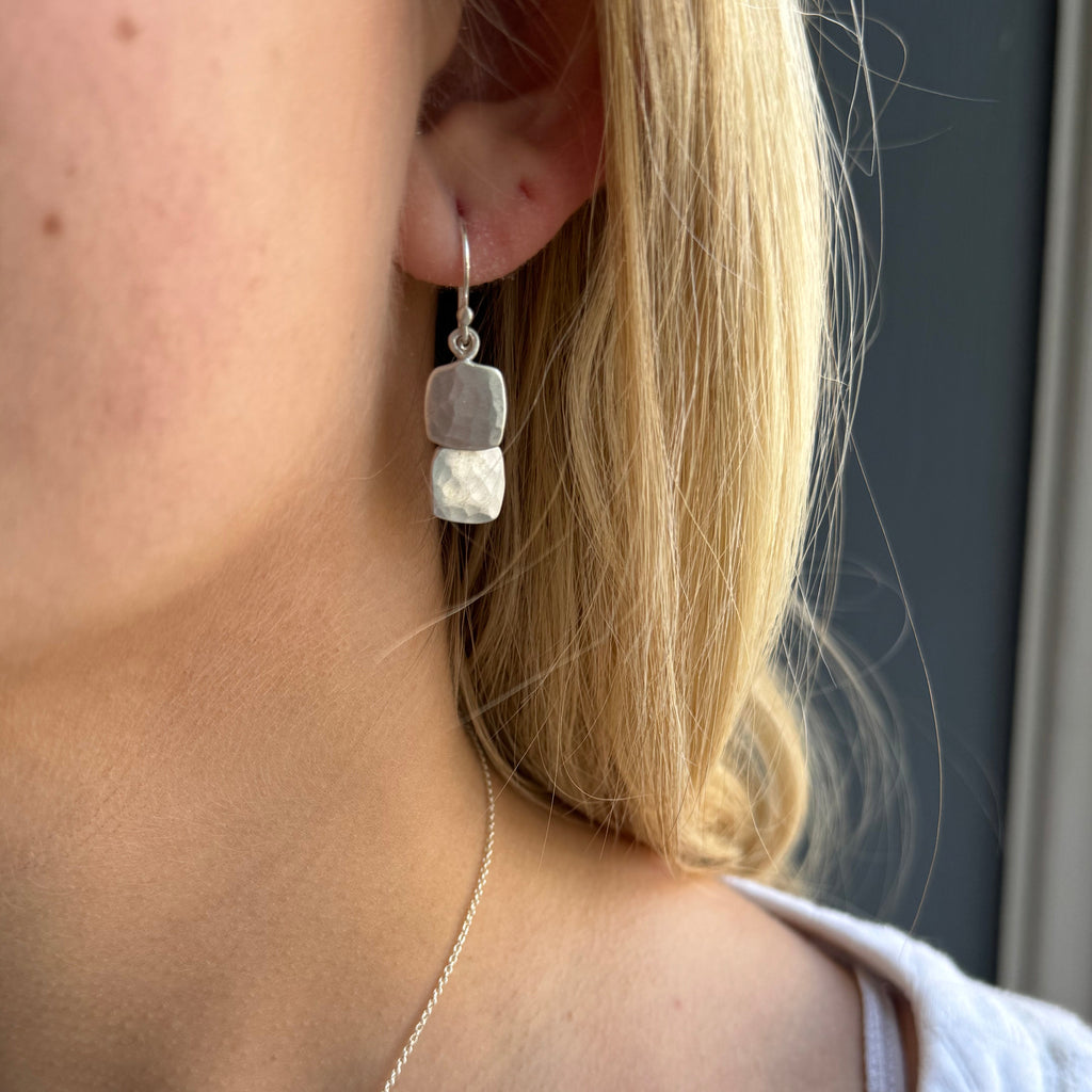 Close-up of a person wearing a delicate necklace with a beaded design.
