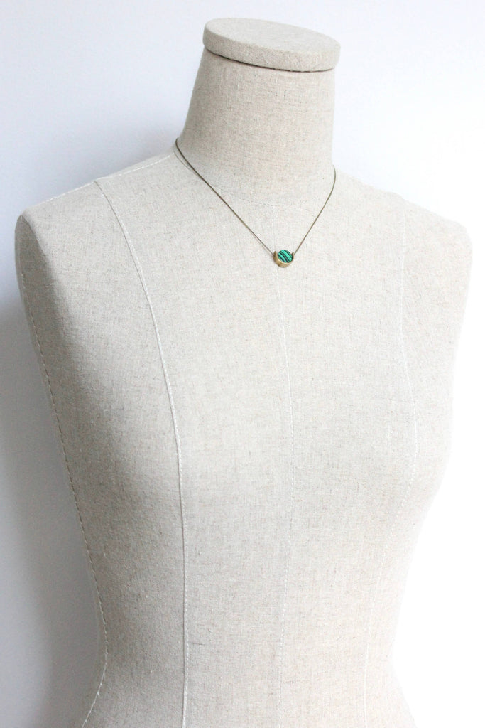 Necklace with a green pendant on a mannequin bust against a white background