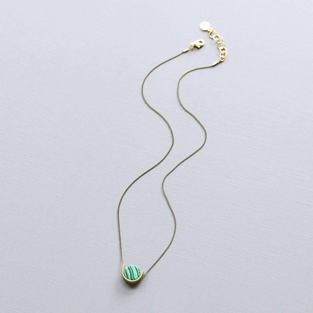 Necklace with a green pendant on a light gray background