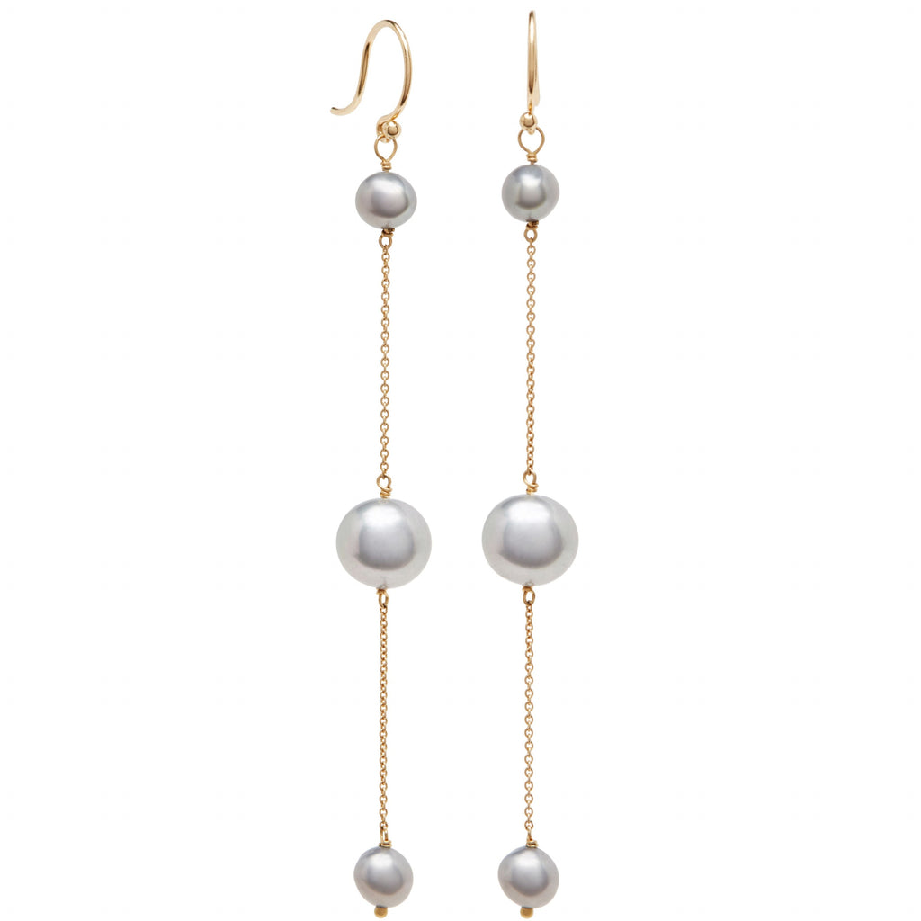 Pair of long linear pearl drop earrings with gold chains on a white background