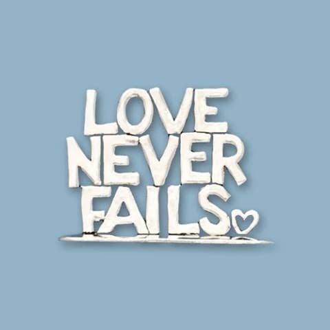 Love Never Fails Small Standing Word Plaque on blue background