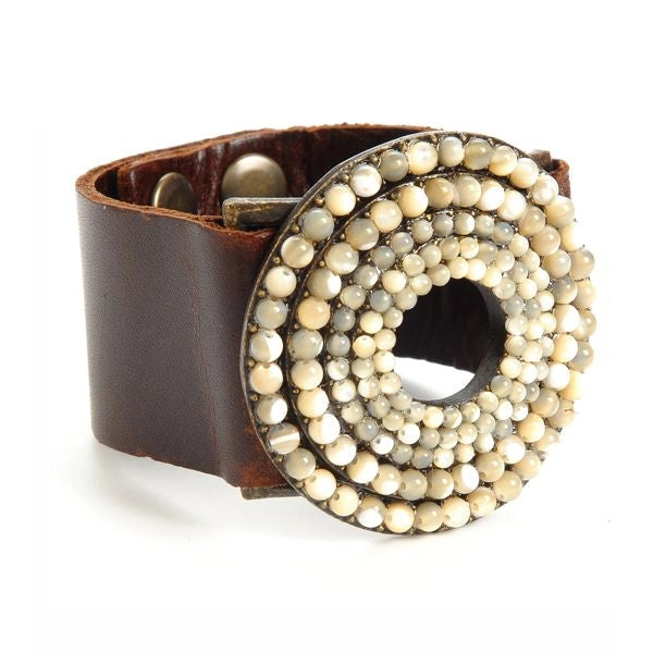 A leather bracelet with a series of mother of pearl beads arranged in a circular pattern, ending with a snap closure.