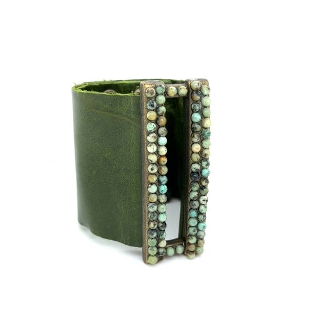 A green rectangle-wide leather bracelet with a brass-finished centerpiece and turquoise stones, closed with a snap button.