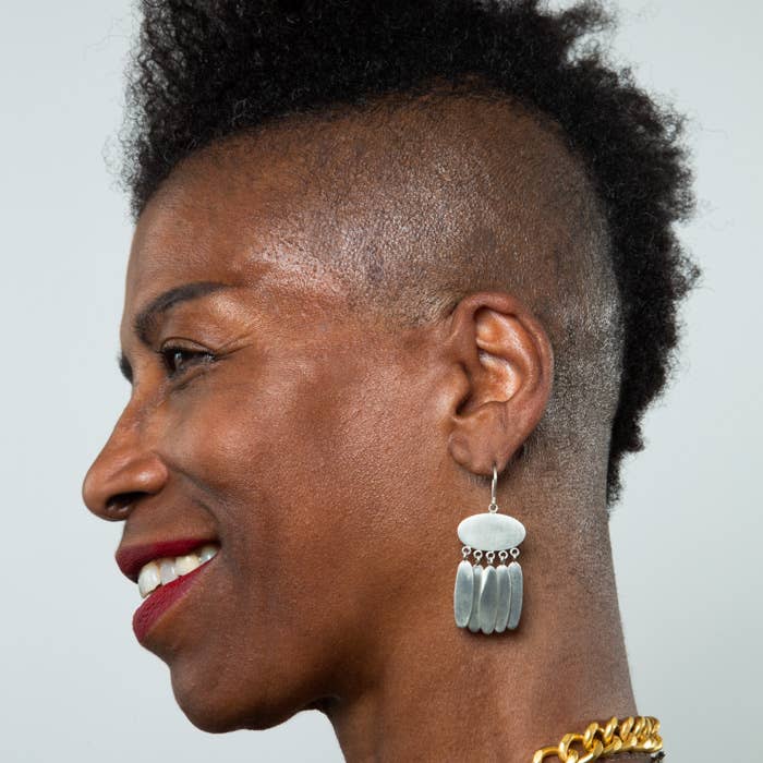 Side profile of a model wearing large earrings with a plain background