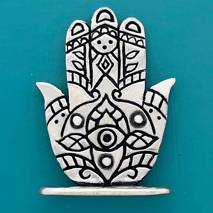 Decorative metal Hamsa hand on a teal background