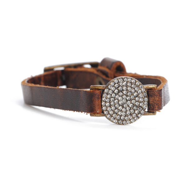 A brown leather bracelet with a round pave disc adorned with black diamond crystals and an adjustable buckle.