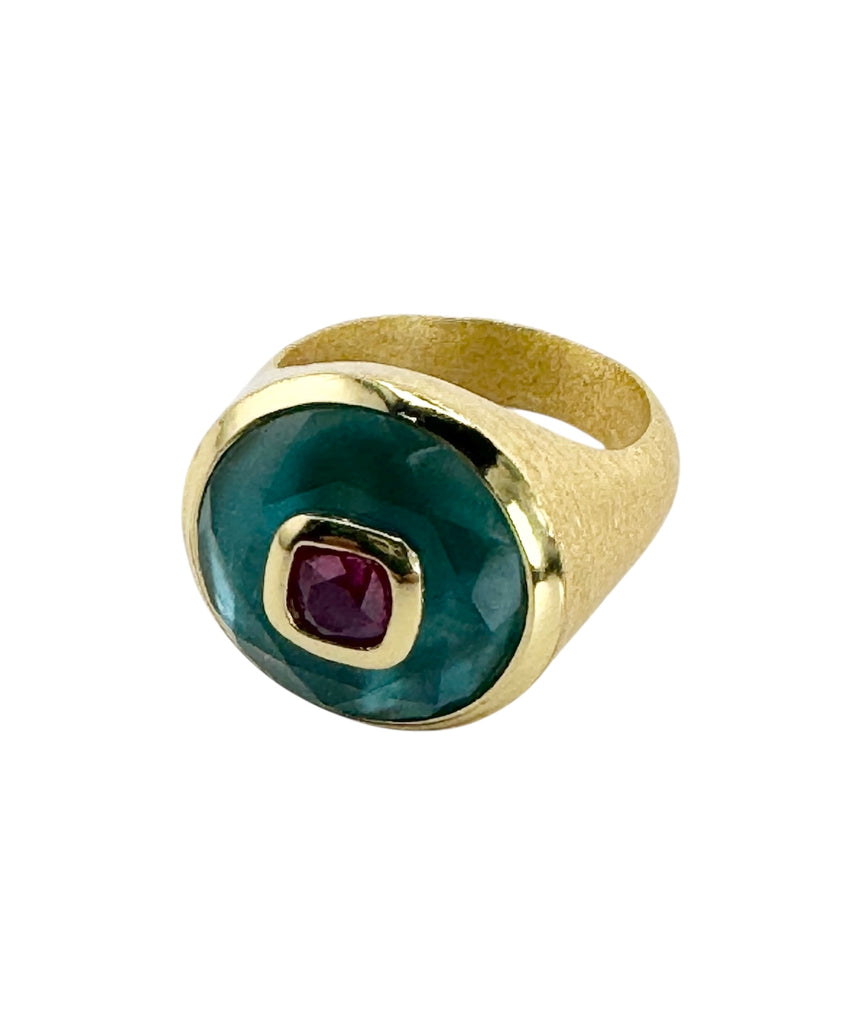 Gold ring with a green gemstone and red stone on a white background