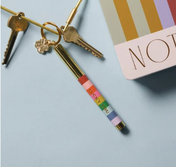 Colorful pen with keychain attachment on a light blue background