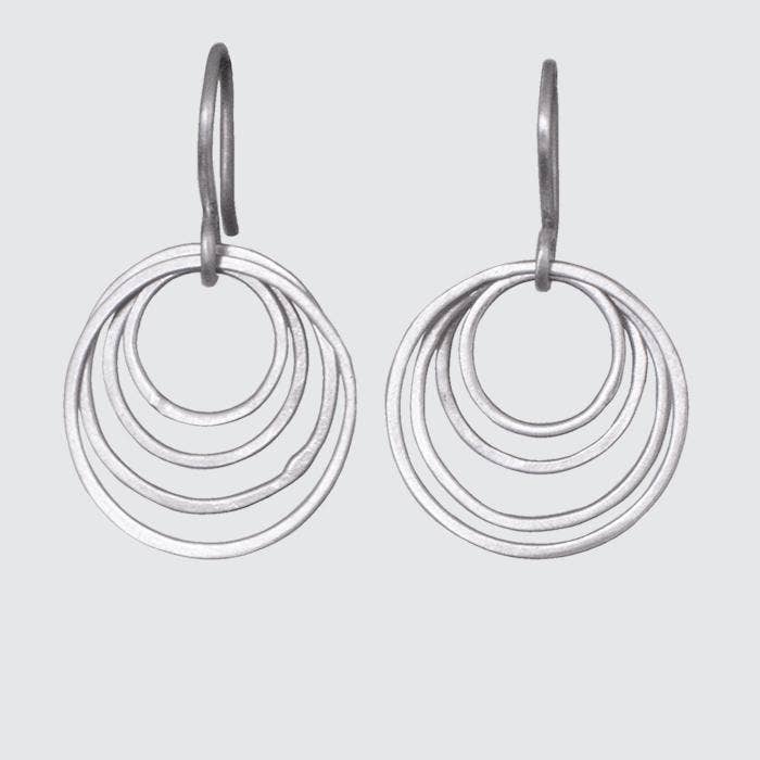 Pair of silver hoop earrings with multiple concentric circles on a light gray background