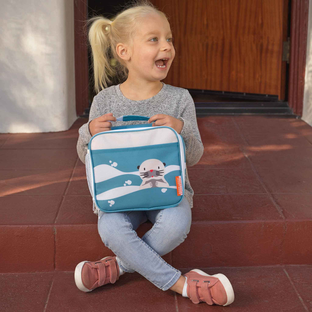 Child holding a lunch bag with a otter design on a red tiled step.