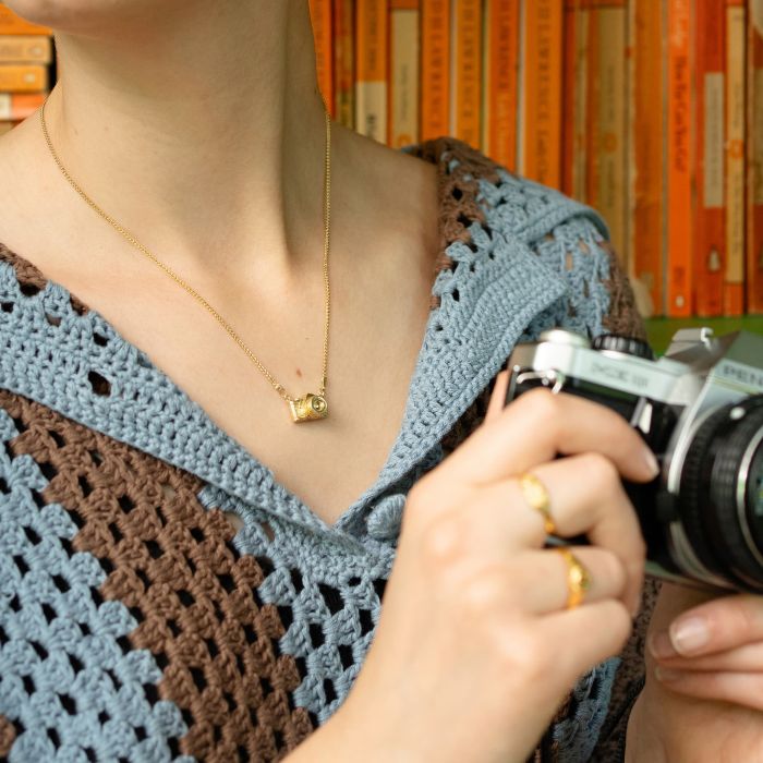 model wearing gold plate camera necklace from neck down