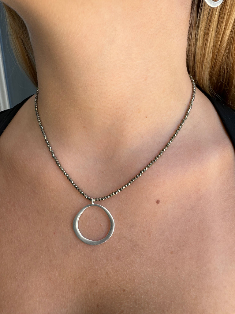 Necklace with a circular pendant on a person's neck