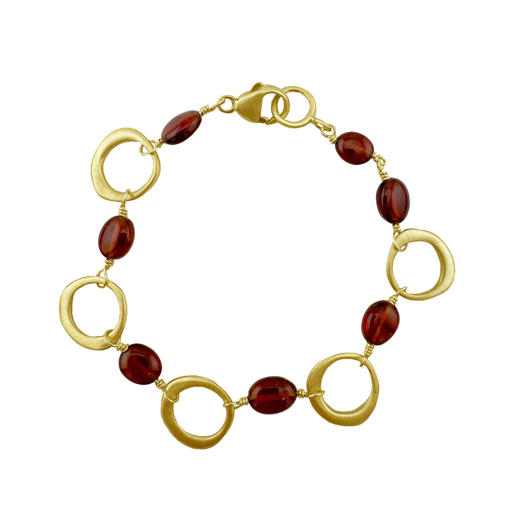 Bracelet with gold loops and red beads on a white background