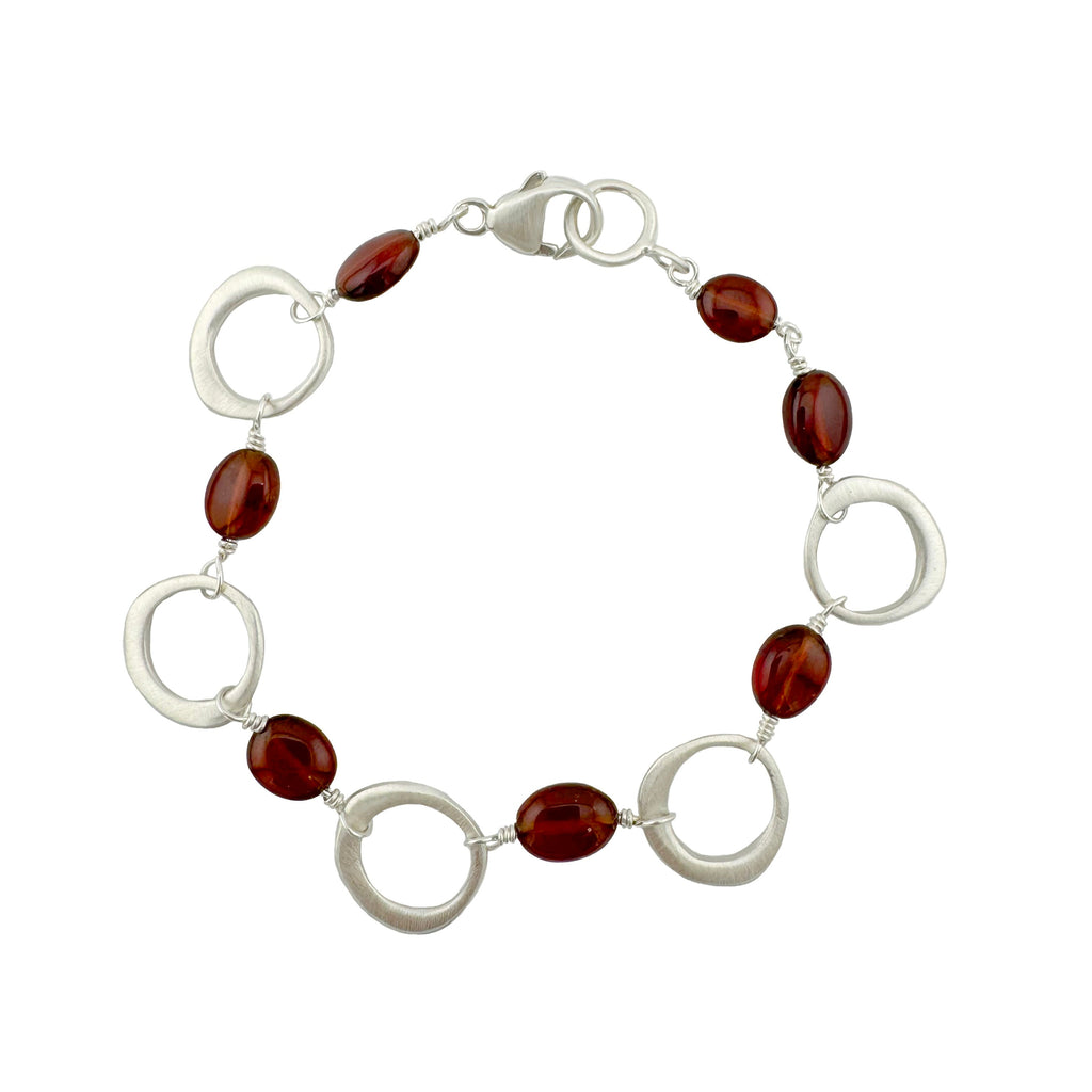 Bracelet with red beads and silver circular links on a white background