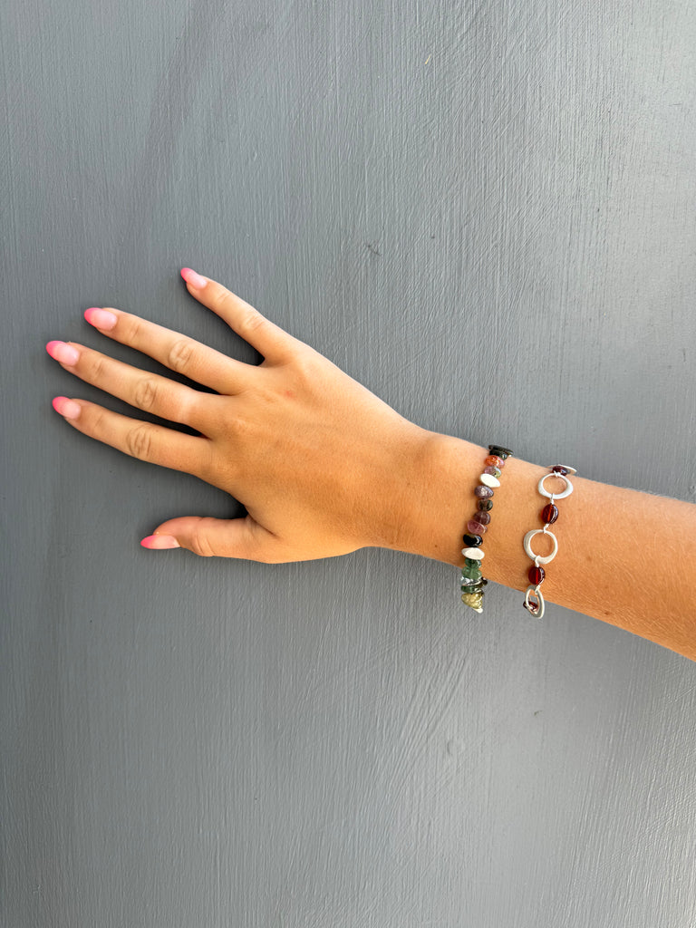 Hand wearing two bracelets on a gray background
