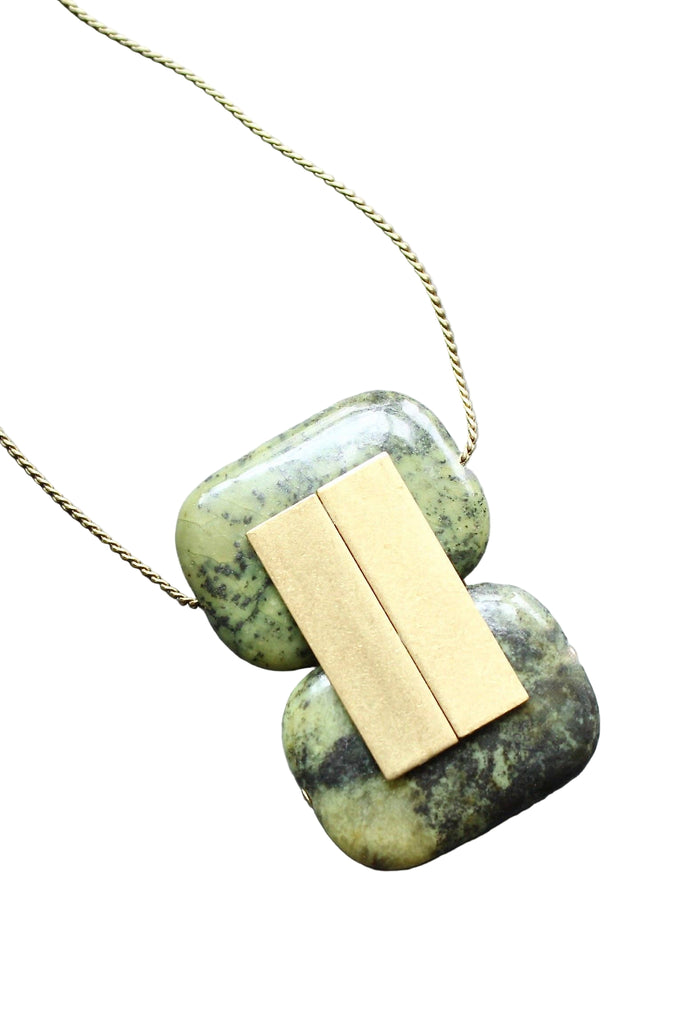 Necklace with green stone pendant and gold bar on a white background
