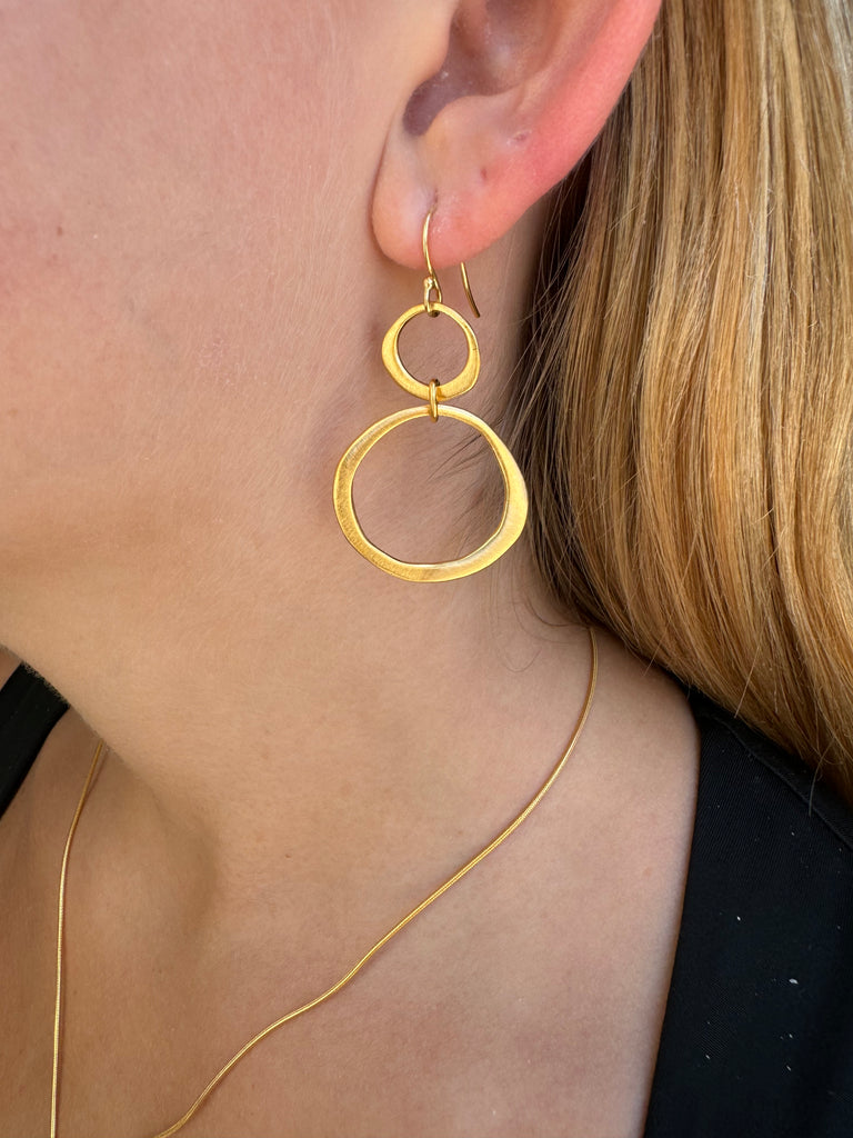 Close-up of a person wearing a gold hoop earring with a blurred background