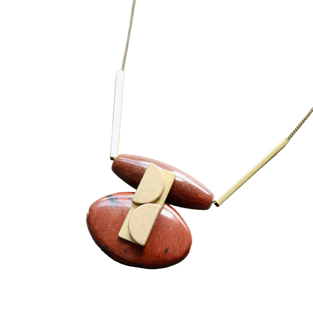 Necklace with red stone pendant and gold accents on a light gray background