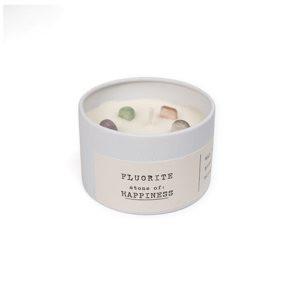 Candle in a container labeled 'Fluorite stone of happiness' on a white background