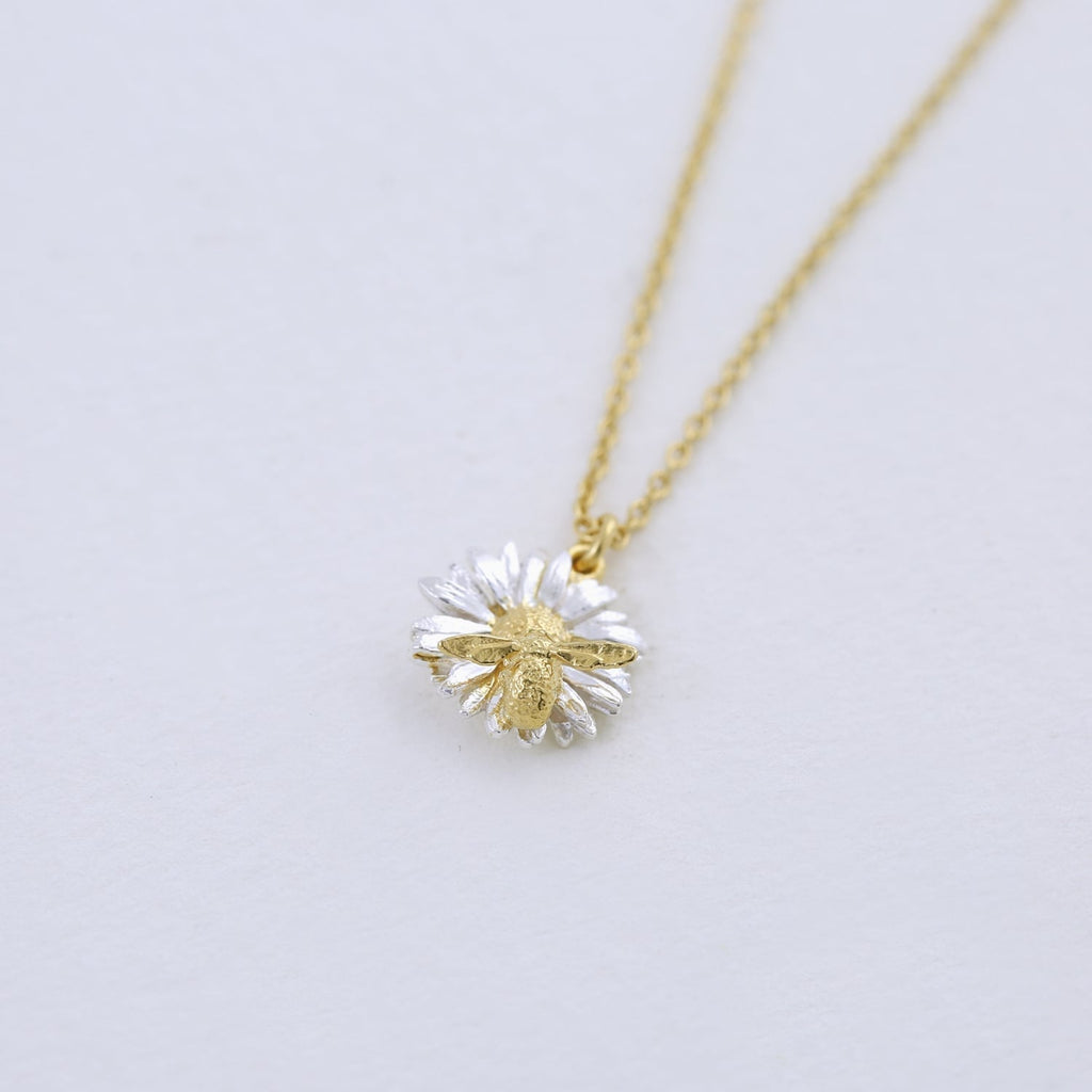 Gold and silver necklace with a flower pendant on a light gray background