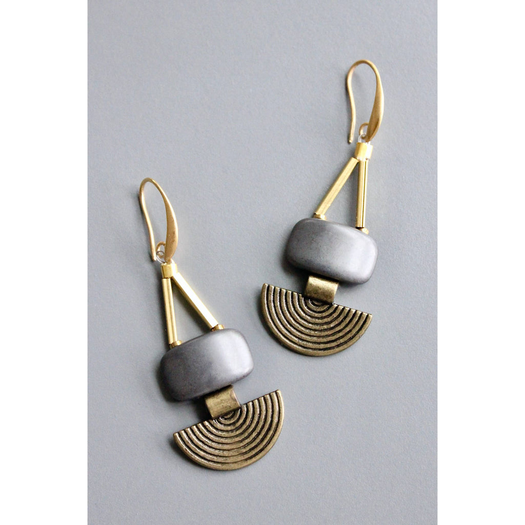 Pair of geometric earrings with gold and silver design on a gray background