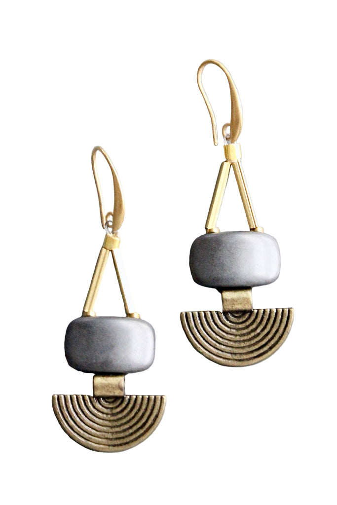 Pair of geometric earrings with gold and silver design on a gray background