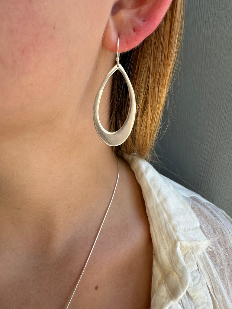 Close-up of a person with a silver earring on their ear lobe.