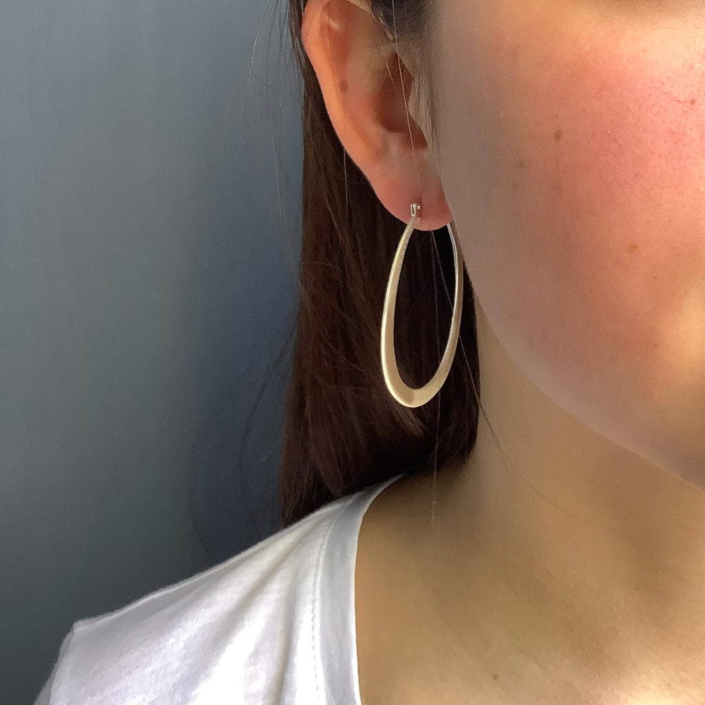 medium oval hoops earrings in silver on the ear
