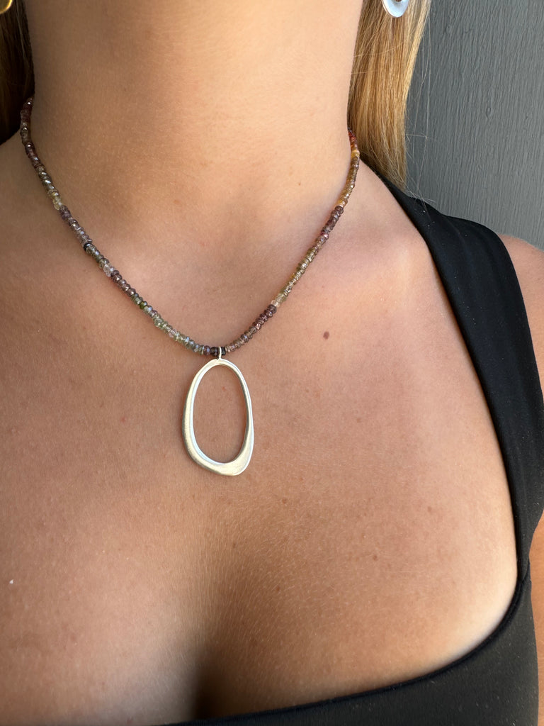 Necklace with a large oval pendant worn by a person