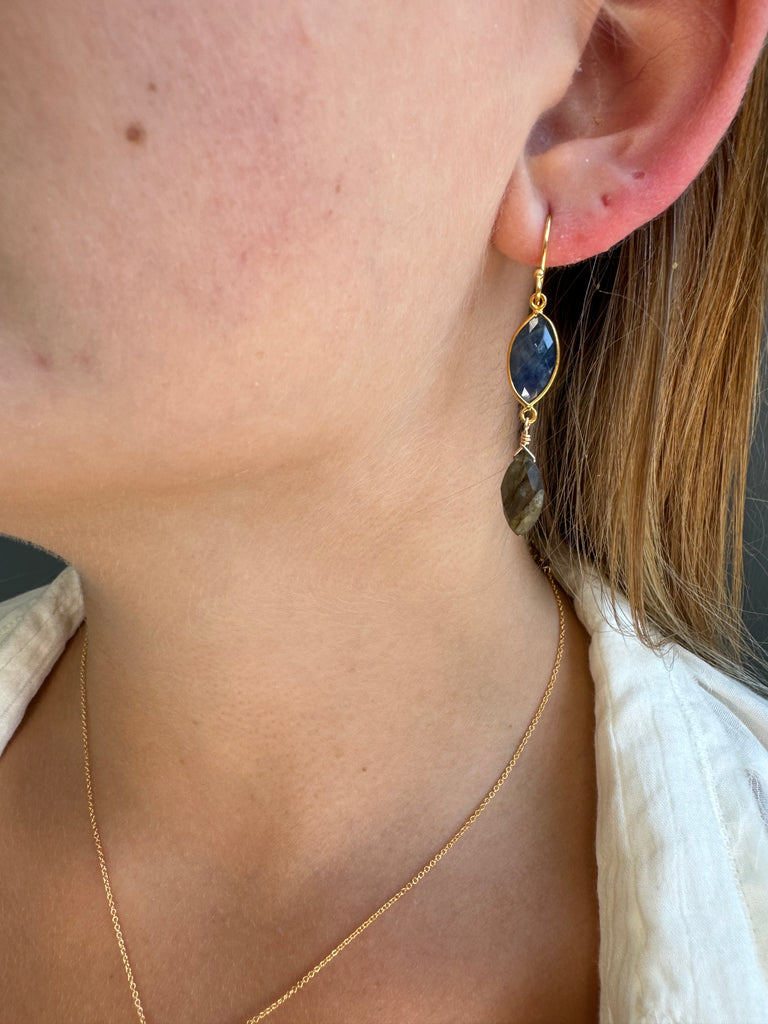 Close-up of a gold earring with blue stones on a person's ear