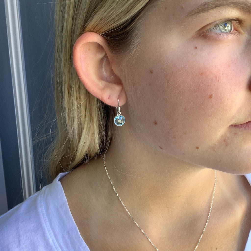 small round swiss blue topaz earrings in silver on the ear