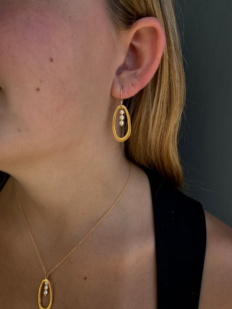 Close-up of a gold earring worn by a person with blonde hair.