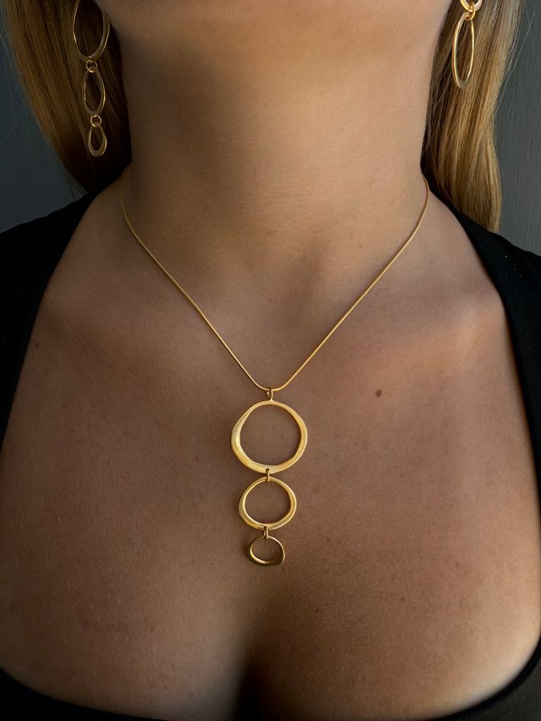 Gold body chain worn by a person on a neutral background