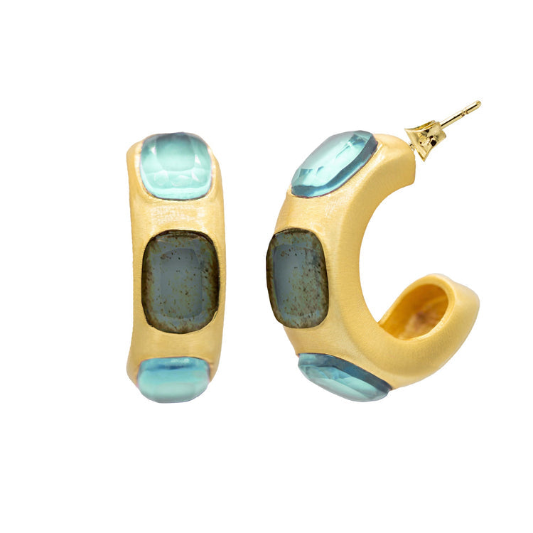 Gold hoop earrings with blue gemstones on a white background