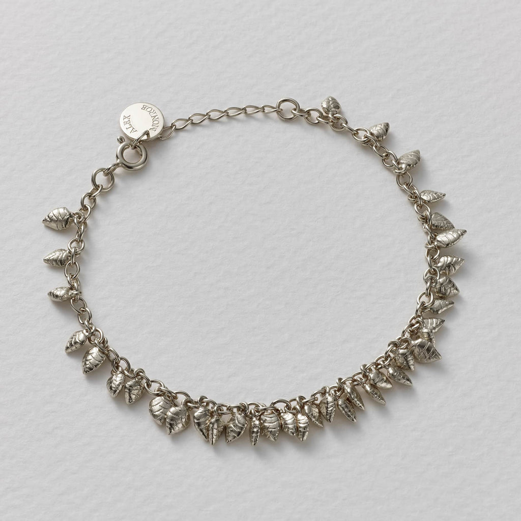 Silver bracelet with leaf-like charms on a light gray background