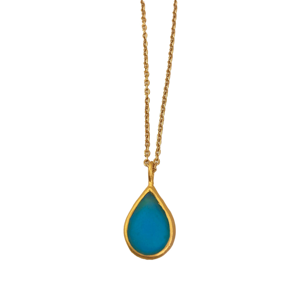 A gold-plated necklace with a bronze tear drop-shaped pendant featuring a teal cast glass element.